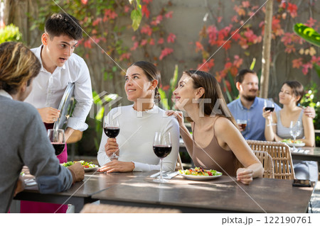 Waiter talking to restaurant guests - taking orders for food and drinks 122190761