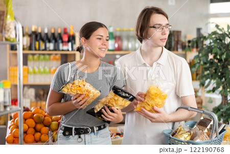 European youth girl and guy choose and buy chips and potato mix crisps in store 122190768