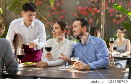 Waiter talking to restaurant guests - taking orders for food and drinks Waiter talking to restaurant guests - taking orders for food and drinks 122190769