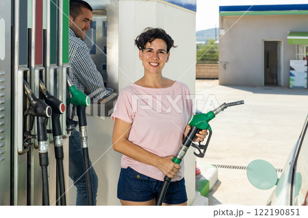 Latin woman filling up tank of her car with gasoline in gas station 122190851