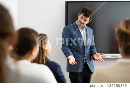 Young male tutor teaching students in college classroom 122190856