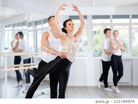 Graceful couple of ballet dancers performing supports at group class Graceful couple of ballet dancers performing supports at group class 122190974