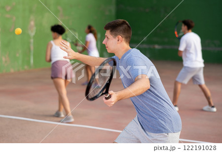 Male sportsman preparing to hit ball with racket. Frontenis game on outdoor court 122191028
