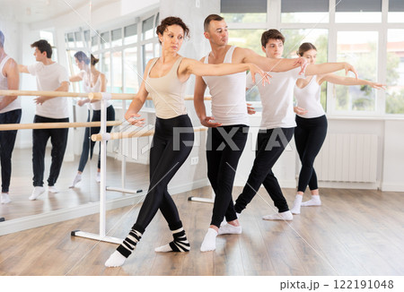 Woman mastering demi rond de jambe at barre at ballet group class 122191048