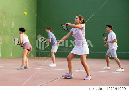 Young hispanic woman playing frontenis on open court in summer 122191060