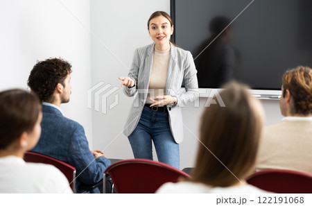 Young female tutor teaching students in college classroom 122191068