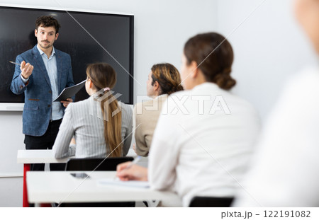 Young male teacher giving lecture to group of student 122191082