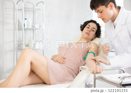 Male anesthesiologist injecting anesthetic into vein on her arm with syringe in cosmetology clinic Male anesthesiologist injecting anesthetic into vein on her arm with syringe in cosmetology clinic 122191155
