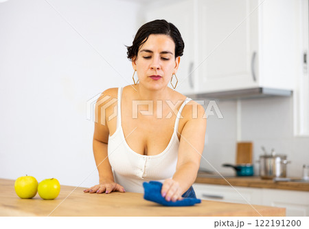 Woman cleaning kitchen countertop with cleaning spray and rag Woman cleaning kitchen countertop with cleaning spray and rag 122191200