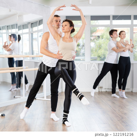 Ballet partners mastering paired technique at group class in studio 122191216