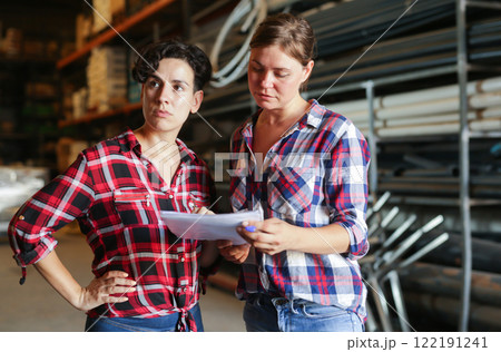 Female warehouse owner and manager keep track of products in warehouse Female warehouse owner and manager keep track of products in warehouse 122191241