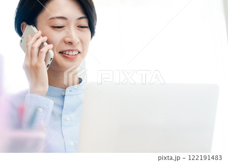 パソコンの画面を見ながら電話をする若い女性 パソコンの画面を見ながら電話をする若い女性 122191483