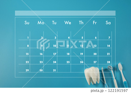 with numbers 1-31. A toothbrush and a pair of dental tools are placed on the calendar 122191597