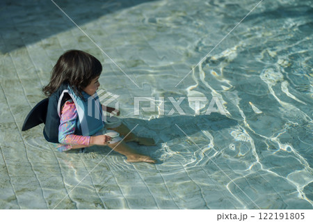happy toddler baby girl in life jacket playing water in swimming pool 122191805