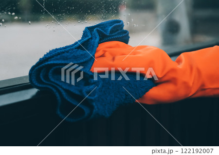 Young female worker cleaning window glass with cloth in spacious villa 122192007