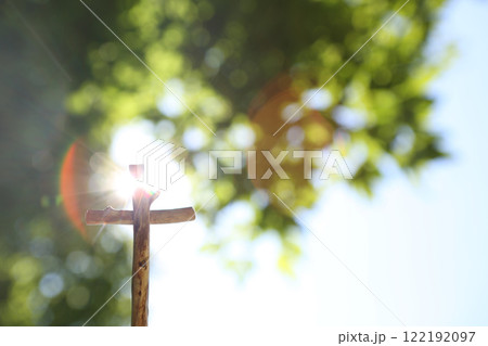 Bright sunlight shines through the blue sky and leaves, illuminating the cross of Jesus Christ. Bright sunlight shines through the blue sky and leaves, illuminating the cross of Jesus Christ. 122192097
