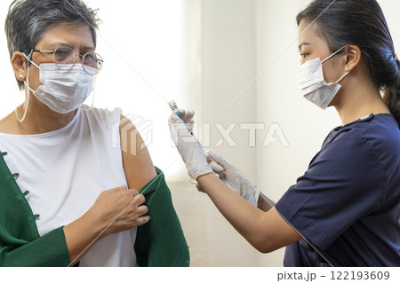 Elderly Asian woman getting coronavirus vaccine by nurse. Medical worker prepare syringe. 122193609