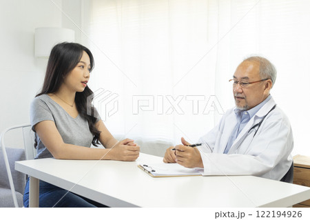 Senior Asian doctor talking with young female patient in hospital. Senior Asian doctor talking with young female patient in hospital. 122194926