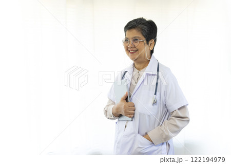 Confident senior female doctor standing by the window in clinic. Confident senior female doctor standing by the window in clinic. 122194979