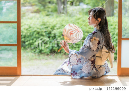 古民家の縁側に座って、団扇で扇いで涼む若い女性 古民家の縁側に座って、団扇で扇いで涼む若い女性 122196099