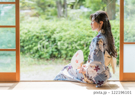 古民家の縁側に座って、団扇で扇いで涼む若い女性 古民家の縁側に座って、団扇で扇いで涼む若い女性 122196101