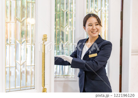 結婚式場のドアを開けるウェディングプランナー・ドアスタッフ・ホテリエの女性(結婚式スタッフ) 結婚式場のドアを開けるウェディングプランナー・ドアスタッフ・ホテリエの女性(結婚式スタッフ) 122196120