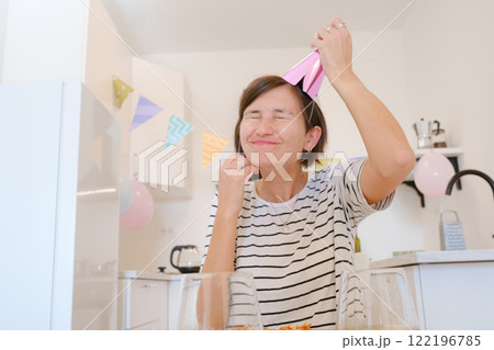 Young woman celebrates birthday at home, surrounded by cozy atmosphere and festive decorations. She enjoys her special day with cake, candles, and warmth, creating memories in relaxed, joyful setting Young woman celebrates birthday at home, surrounded by cozy atmosphere and festive decorations. She enjoys her special day with cake, candles, and warmth, creating memories in relaxed, joyful setting 122196785