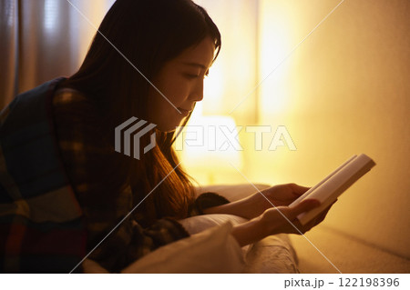 布団を被り読書をする日本人の女性 122198396