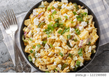 Spicy Mexican corn potato salad with hard boiled eggs, onions and pickled jalapenos and cheese close-up in a plate. horizontal top view 122198980