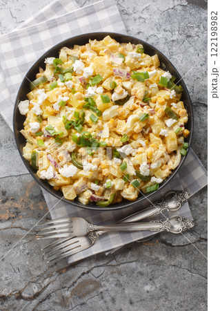 Mexican Street Corn Potato Salad with spicy jalapenos, boiled eggs, fresh green and red onions, and salty cotija cheese closeup on the plate. Vertical top view 122198982