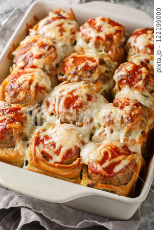 Garlic Bread Meatball Bombs are dinner rolls stuffed with a meatball and sauce, then topped with cheese closeup on the baking dish. Vertical Garlic Bread Meatball Bombs are dinner rolls stuffed with a meatball and sauce, then topped with cheese closeup on the baking dish. Vertical 122199000