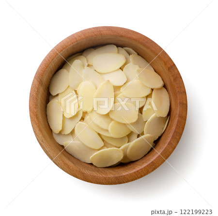 Almond flakes in a wooden plate close-up on a white. Top view 122199223