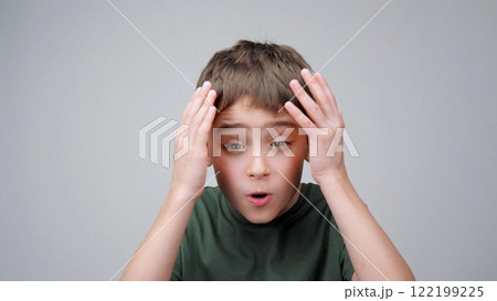 Portrait surprised child. Face boy opening mouth and putting hands on head. Child amazed and experiencing shock, wow. Child emotion wow. Concept expressing delight and joy. Portrait surprised child. Face boy opening mouth and putting hands on head. Child amazed and experiencing shock, wow. Child emotion wow. Concept expressing delight and joy. 122199225