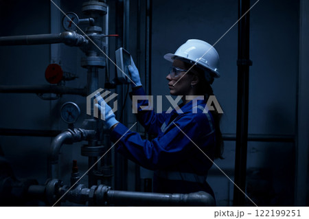 Engineer Inspecting Industrial Machinery in Dimly Lit Factory Environment 122199251
