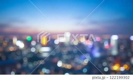 Blurred city skyline at dusk with colorful lights and soft glowing bokeh effect. Urban nightscape background showing abstract view of buildings and lights, business, travel 122199302