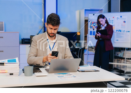 Business man working at office with laptop and documents on desk, financial adviser analyzing data, employees working overtime. Business man working at office with laptop and documents on desk, financial adviser analyzing data, employees working overtime. 122200076