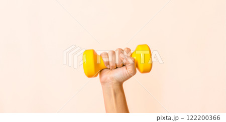 Fitness concept with hand holding yellow dumbbell, pink background, workout motivation, strength training, exercise equipment, gym accessory, home gym, physical activity, active lifestyle 122200366