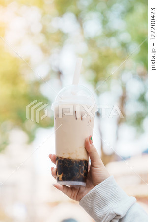 Woman hand holding brown sugar boba milk tea with tapioca pearls, famous Taiwanese bubble tea of Taiwan. Street Food and travel in Ximending, Taipei concept Woman hand holding brown sugar boba milk tea with tapioca pearls, famous Taiwanese bubble tea of Taiwan. Street Food and travel in Ximending, Taipei concept 122200423
