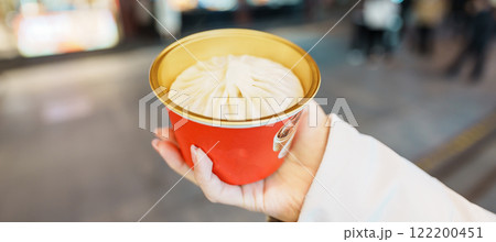 woman traveler visiting in Shanghai, China. Happy Female Tourist eating Xiaolongbao in Yuyuan Old Street market at night. landmark and popular for tourism attractions. Travel and Vacation 122200451