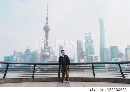 man traveler visiting in Shanghai, China. male Tourist sightseeing Shanghai view of Lujiazui in The Bund of Shanghai. landmark and popular for tourism attractions. Vacation concept 122200453
