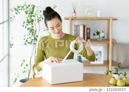 ダンボールを梱包する若い女性 122202037