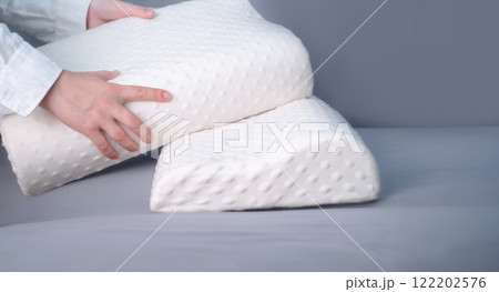 Women’s hands holding memory foam pillows, showcasing quality sleep support for office workers who sit at desks for long hours. Women’s hands holding memory foam pillows, showcasing quality sleep support for office workers who sit at desks for long hours. 122202576
