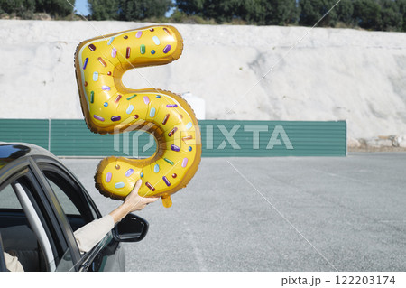 man holding a 5-number-shaped balloon man holding a 5-number-shaped balloon 122203174