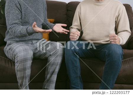 two men are arguing sitting on a brown sofa 122203177