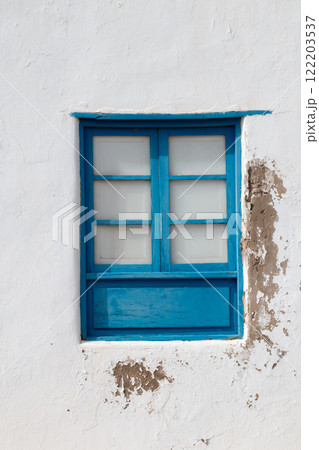 White weathered wall and a blue window, Spain White weathered wall and a blue window, Spain 122203537