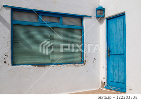 White weathered wall and a blue window and door, Spain White weathered wall and a blue window and door, Spain 122203538