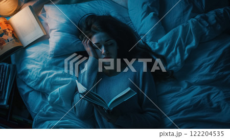 Woman asleep with book in bed. 122204535