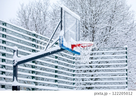 Snow-covered basketball hoop on an outdoors playground in winter Snow-covered basketball hoop on an outdoors playground in winter 122205012