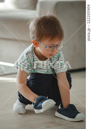 Child with autism in glasses play with his shoes Child with autism in glasses play with his shoes 122205904