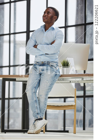 african american man sitting on desk and posing with folded hands 122206621